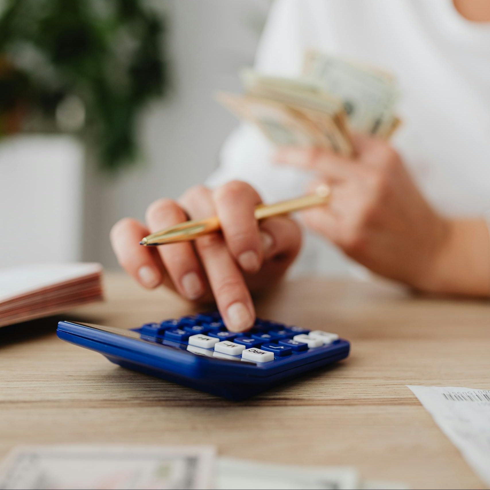 A woman uses a calculator and holds money, illustrating personal finance management.