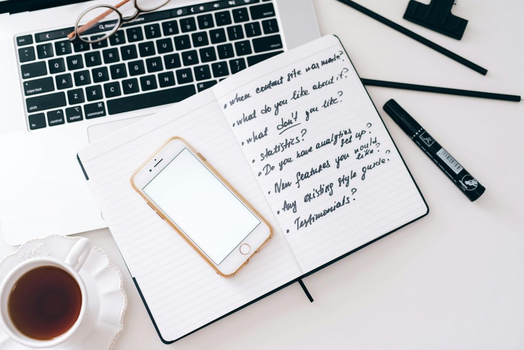 Top view of a workspace setup with a laptop, smartphone, notebook, and cup of coffee. Ideal for productivity.